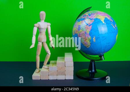Uomo di legno che cammina sulla scala di carriera. Scale sono fatte di mattoni di legno. Manichino in cima allo sviluppo. Il concetto di sviluppo personale, carriera, Foto Stock