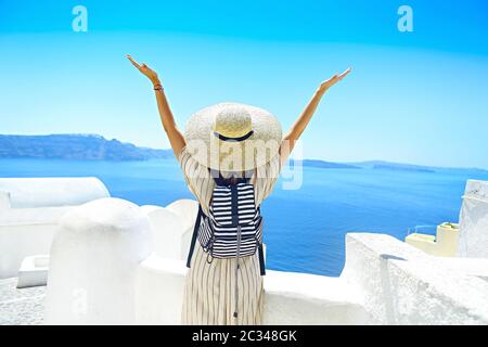 Giovane donna in un abito bianco e cappello di paglia, a piedi nella città di Oia, isola di Santorini, Grecia Foto Stock