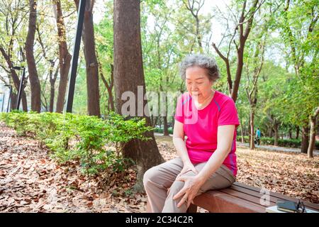 donna anziana che soffre di dolore alle gambe e al ginocchio Foto Stock