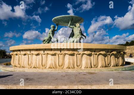 La famosa fontana del Tritone, tre di bronzo Tritons tenendo in mano un enorme bacino, davanti alla porta della città de La Valletta, dimensionabili fontana di pietra miliare con m Foto Stock