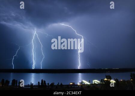 Fulmine nel cielo notturno sopra il fiume Foto Stock