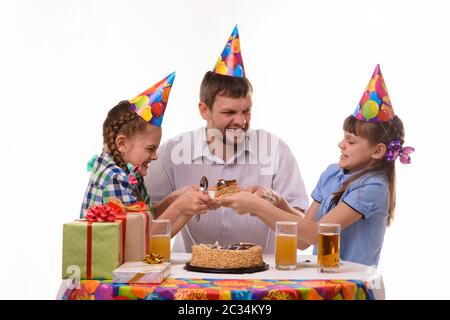 Papà e due figlie lottano per il primo pezzo della torta di festa Foto Stock