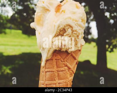 Cono gelato che si fonde all'aperto in estate, dolce cibo da dessert in vacanza Foto Stock