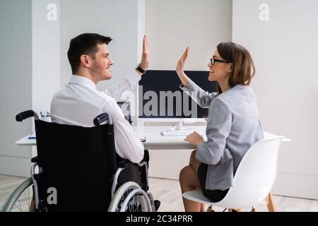 Imprenditore disabili dando alta cinque al suo sorridente Partner femminile in Office Foto Stock