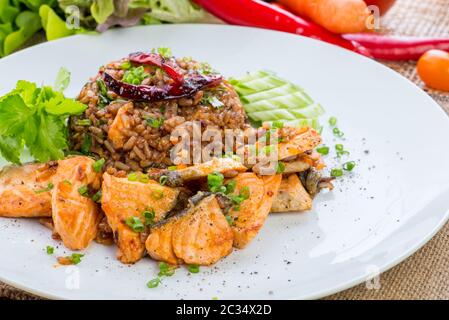 cucina cinese, pesce salmoni e riso fritto all'uovo e verdure con ingredienti su sfondo rustico. Foto Stock