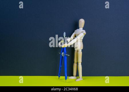 Uomo in legno figurine con bussola sulla tavola gialla. Foto Stock