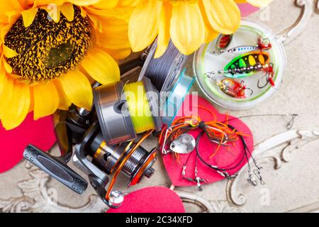 Pesca tackles, linee e mulinello con decorazione primaverile con girasoli e cuori rossi Foto Stock