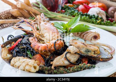 Spaghetti neri alle Vongole. Pasta di pesce nero con vongole e salsa all'aglio di yogurt su tavola nera. Specialità mediterranee, pesce, pasta nera con Foto Stock