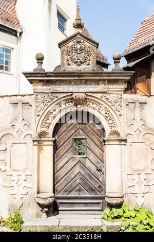 Portale d'ingresso storico del 1616 con iscrizione. Riccamente decorato ad arco con una porta di legno marrone. Foto Stock