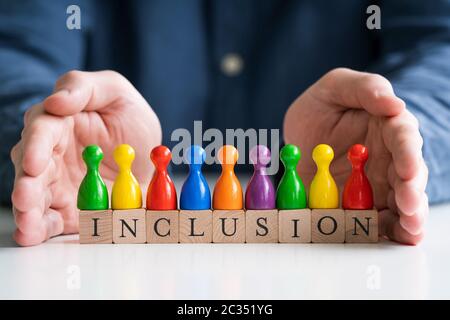 Uomo che protegge testo di inclusione e pedine multicolore Foto Stock