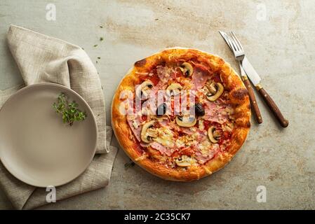 La pizza servita con mozzarella e prosciutto, funghi e salsa di pomodoro Foto Stock