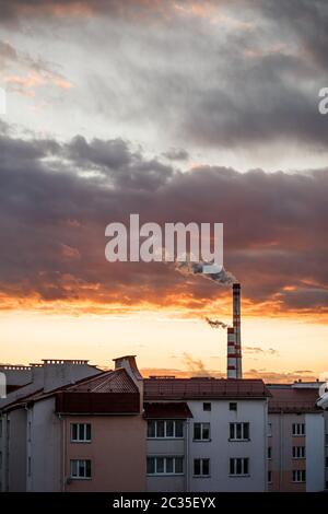 Dai tubi provengono vapore o fumo. Centrale termica ed elettrica combinata in città. Paesaggio al tramonto o all'alba Foto Stock