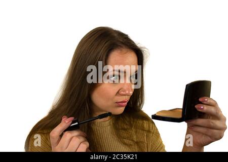 giovane ragazza con capelli marroni e occhi verdi compongono mascara mejk per gli occhi Foto Stock