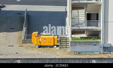 Grande giallo di un generatore di potenza elettrica dietro la costruzione di Foto Stock