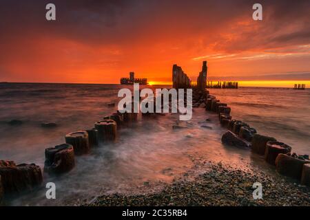 Suggestiva alba sul mare. Luogo famoso sulla costa baltica, spiaggia vicino alla vecchia pianta di siluro dalla seconda guerra mondiale Foto Stock