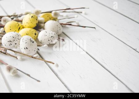 Decorazioni pasquali. Willow ramoscelli e uova decorative su sfondo di legno bianco Foto Stock
