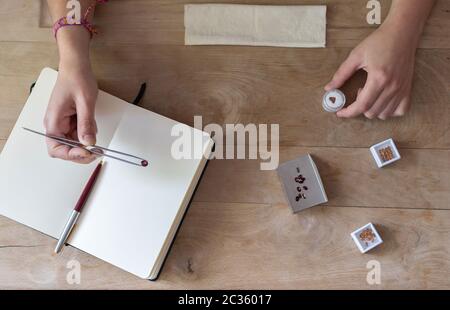 Vista dall'alto del piano di lavoro dei gemologi. Gemma per la presa a mano con pinze per gioielli e diversi attrezzi Foto Stock
