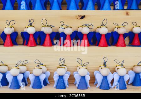 molti angeli in legno fatti a mano su una bancarella mercatino di natale, dipinto in rosso e blu Foto Stock