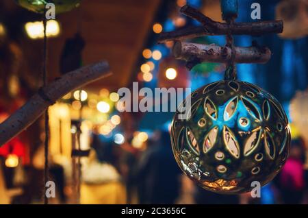 particolare di un mercatino di natale in italia, con una palla di christmas fatta a mano appesa alla luce delle bancarelle illuminate di notte Foto Stock