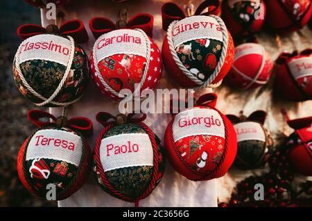 palline di natale artigianali su una bancarella di mercato, decorate con i comuni nomi tradizionali italiani per diventare un regalo personalizzato Foto Stock