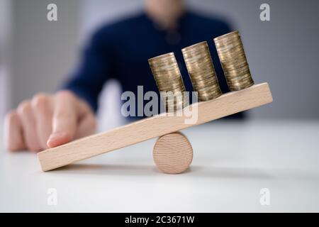 Close-up di un imprenditore crescente di bilanciamento delle monete impilate con il dito sull'altalena Foto Stock