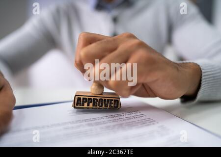 Close-up di mano di una persona Stamping approvato con timbro sul documento alla scrivania Foto Stock