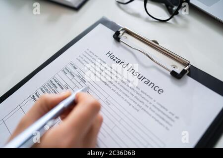 Persona che riempie di pericolo sotto forma di assicurazione alla scrivania Foto Stock