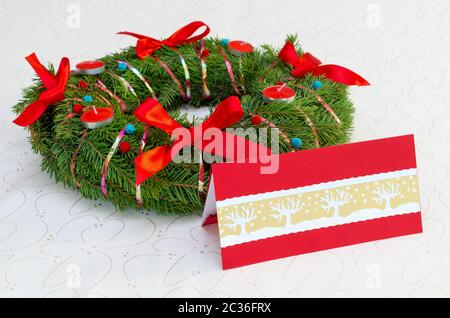 Corona di Natale classica con candele rosse e carta sulla tovaglia Foto Stock