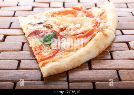 Trancio di pizza italiana su un supporto di legno. Foto Stock