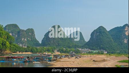 Yangshuo, Cina - Agosto 2019 : vista panoramica del fiume OLi shore con piccolo turista e barche di pescatori sulla riva del fiume, la traversata in traghetto e puntare Foto Stock