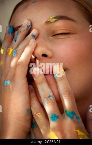 Closeup foto di una ragazza sognante con occhi chiusi e mani colorate in vernice, pittori mondo interno, foto concettuale di artisti creativi con una nuova idea Foto Stock