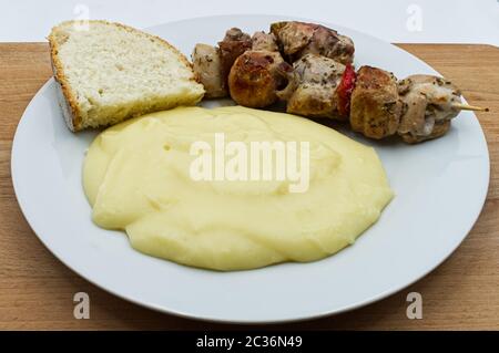 Carne di pollo su spiedino di legno con fetta di pane e purè di patate cremoso fatto in casa Foto Stock