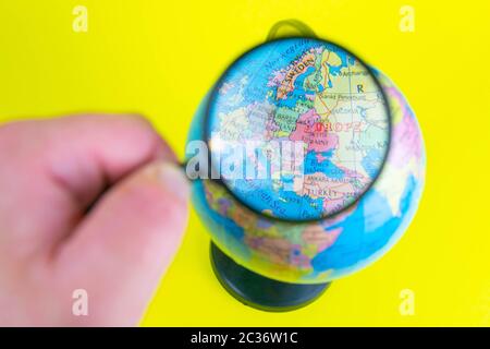 Primo piano di una mano che tiene una lente di ingrandimento per guardare il globo nella biblioteca selettiva fuoco Ucraina. Foto Stock