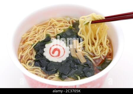 Primo piano di tagliatelle istantanee, zuppa di noodle in una tazza con bastoncini Foto Stock