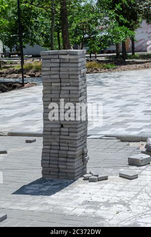 Il processo di posa di lastre di pavimentazione in un parco cittadino. Lastre di pavimentazione grigie piegate in una colonna. Ricostruzione dell'area di intrattenimento e ricreazione di Foto Stock