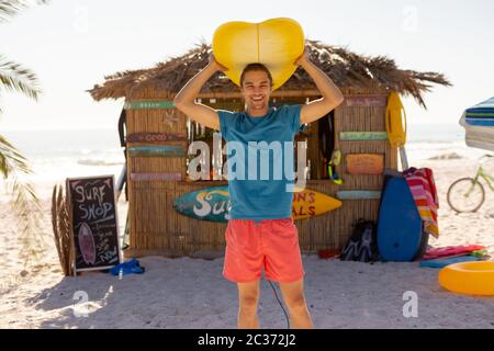 Uomo caucasico che tiene surf board sulla spiaggia Foto Stock