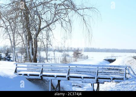 Ponte di legno nella neve. Idilliaco scenario rurale Foto Stock