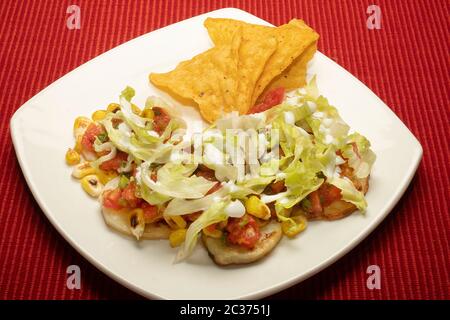 PATATE MESSICANE CON PATATINE DI MAIS, MAIS CARRINATO, CONDITO CON LATTUGA, PANNA ACIDA E SALSA Foto Stock