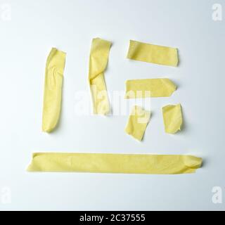 Set di vari pezzi di colore giallo appiccicoso del nastro di carta su uno sfondo bianco, close up Foto Stock