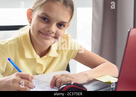 Ritratto closeup di ragazza felice che fa i compiti davanti allo schermo del computer Foto Stock
