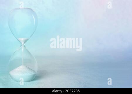 Concetto di tempo. Una clessidra con il periodo che arriva alla fine, con spazio di copia, in blu teale, immagine tonata Foto Stock
