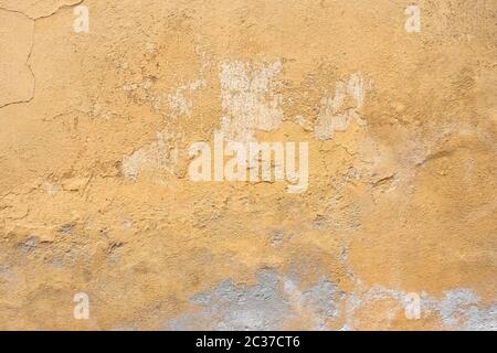 Grunge parete intonaco con sfondo giallo graffiato. Vecchio muro con buccia color palude stucco texture. Carta da parati vintage. Decadimento e crepe. Abstra ruvida Foto Stock