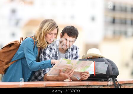 Coppia di turisti parlando controllo mappa su carta in vacanza in piedi all'aperto in un balcone in un paese rurale Foto Stock