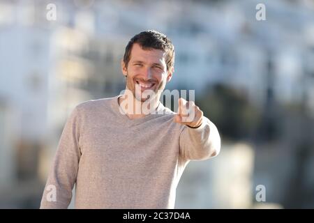 Vista anteriore verticale di un adulto felice l'uomo puntando alla fotocamera in piedi in un paese rurale Foto Stock