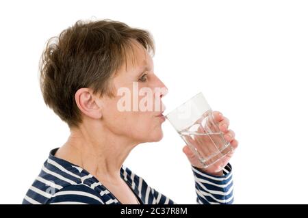 Profilo della testa e delle spalle di una donna anziana in una camicia a righe che tiene un bicchiere d'acqua alla bocca su sfondo bianco. Foto Stock