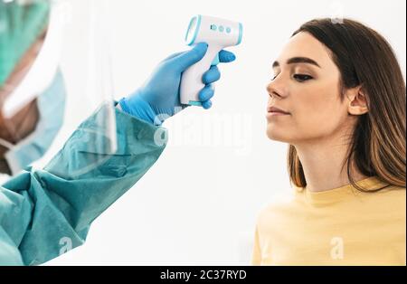 Medico misurazione della temperatura con nuovo termometro digitale per la giovane paziente durante la pandemia del virus corona - cura sanitaria e attrezzature mediche conc Foto Stock