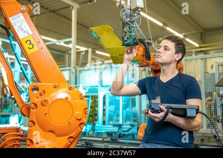 programmazione di bracci robot per un nuovo prodotto da parte di un tecnico di produzione. Foto Stock