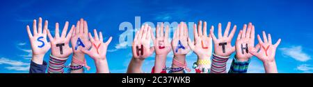Bambini mani tenere colorato inglese parola rimanere sano. Cielo blu come sfondo Foto Stock