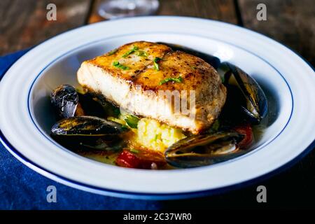 Filetto di pesce fritto con cozze in un piatto sul tavolo. Foto Stock