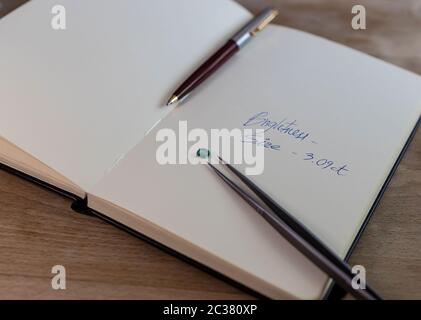Pietra smeraldo su un notebook con note, clip di gioielli e penna Foto Stock